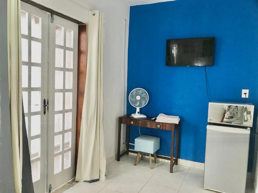 Una habitación con una pared azul y una mesa con ventilador. en Suíte céu azul, en Cabo Frío