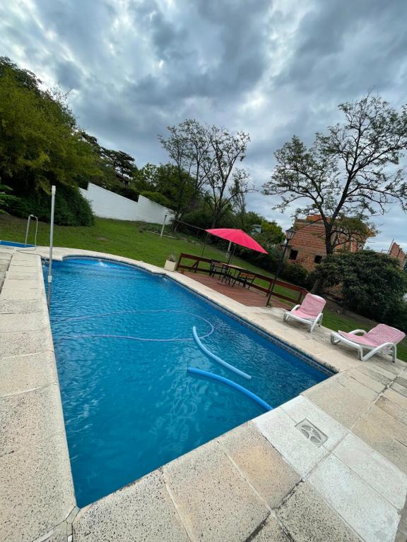 a swimming pool with a pink umbrella and a picnic table at Apartamento Remansum in Santa Rosa de Calamuchita