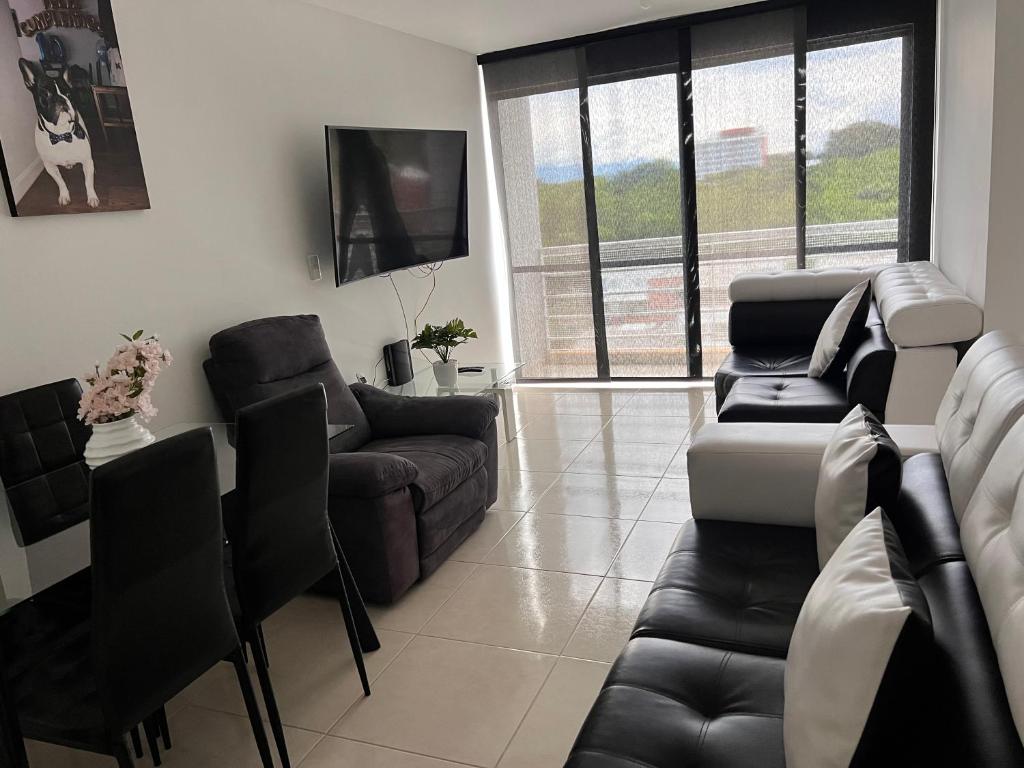 sala de estar con sofá, sillas y TV en Apartamento en Pereira, en Pereira