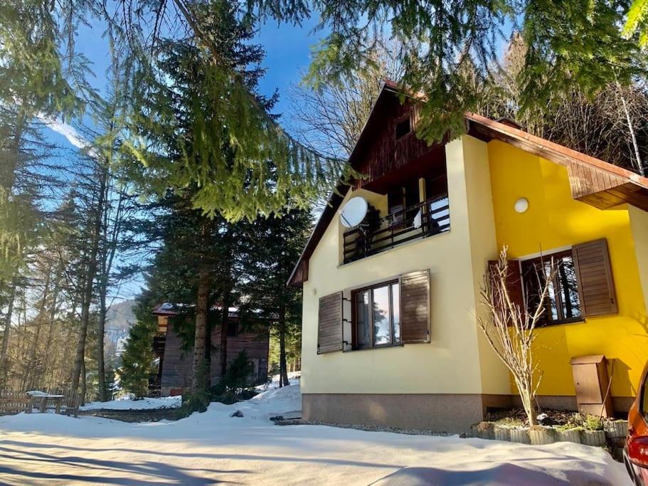 a yellow house with snow in front of it at Chalet Pohoda in Donovaly