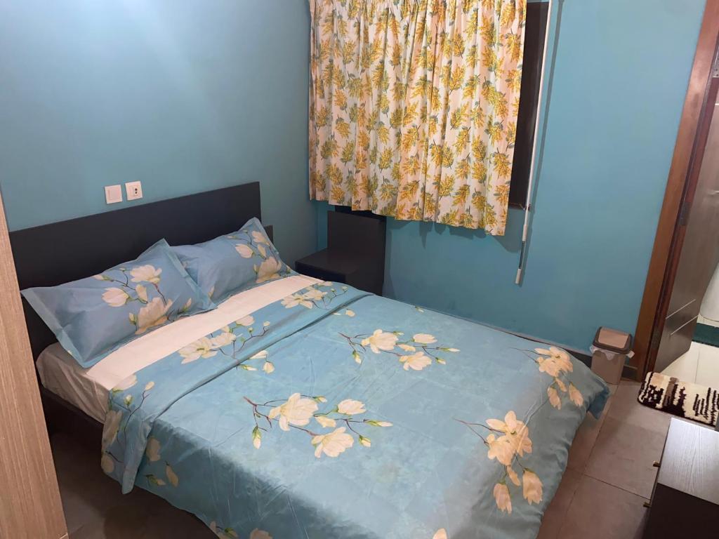 a bed with a blue comforter with flowers on it at THE LANDING LODGE-ABIDJAN in Abidjan