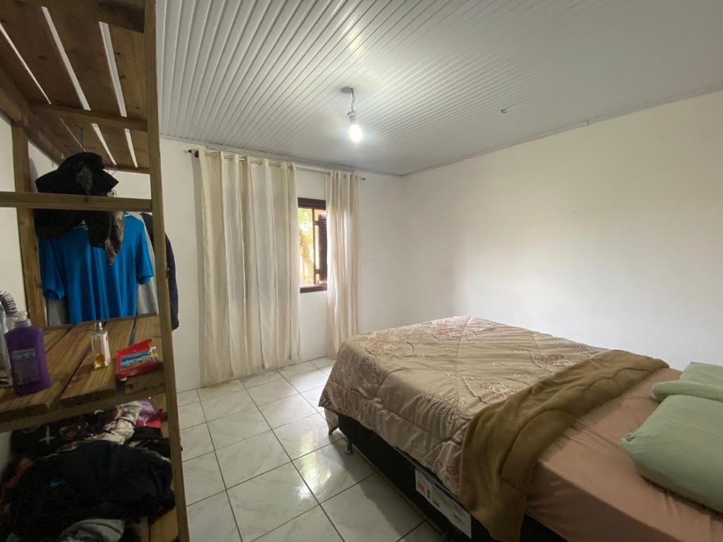 ein Schlafzimmer mit einem Bett in einem Zimmer mit einem Fenster in der Unterkunft Casa de veraneio in Arroio do Sal