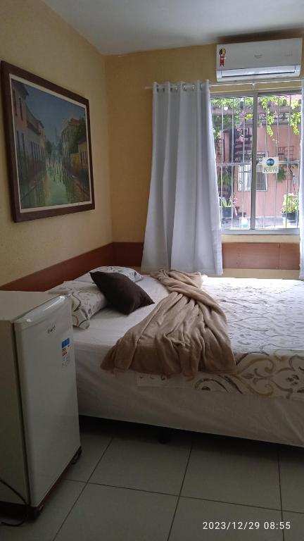 a bedroom with a bed with a window and a white curtain at Hospedaria FOR755 in Fortaleza