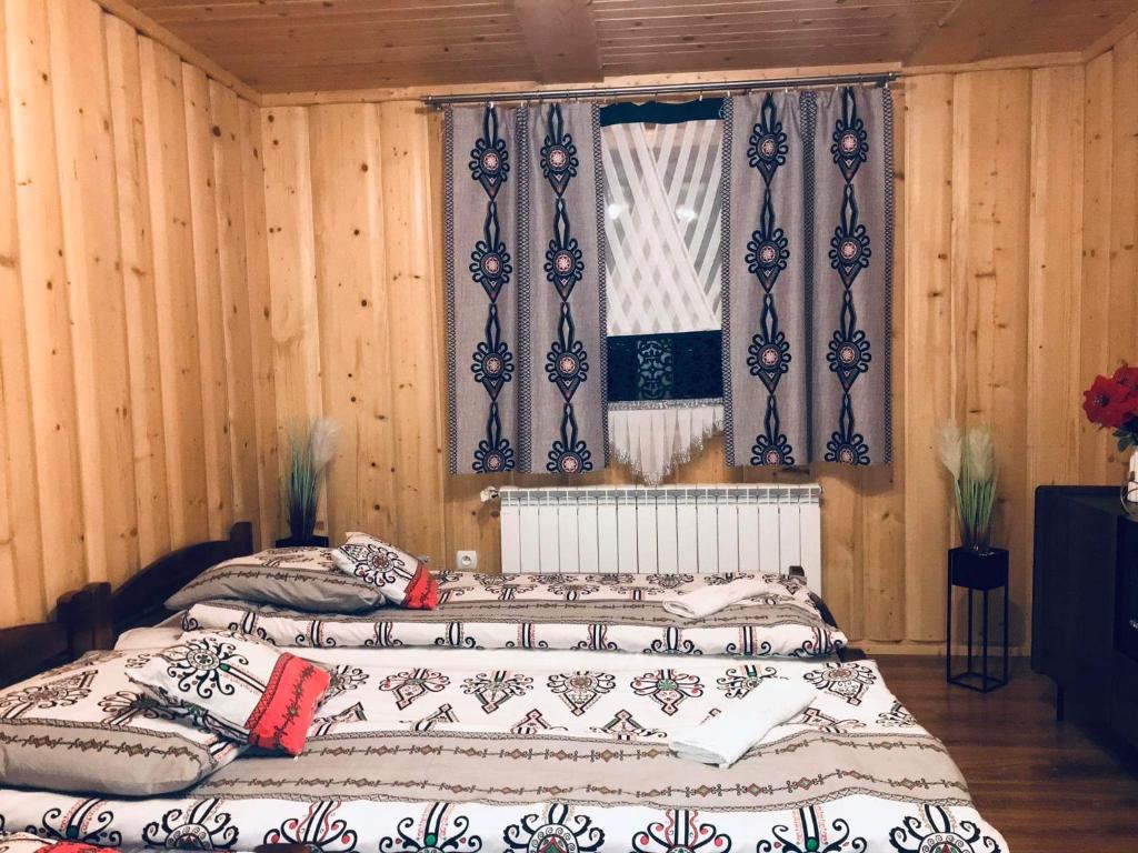 a bedroom with a large bed with wooden walls and windows at Chata na Grapie in Biały Dunajec