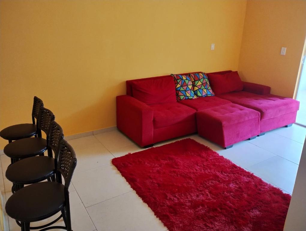 a living room with a red couch and a red rug at Apartamento Mangaratiba 2 suites in Mangaratiba