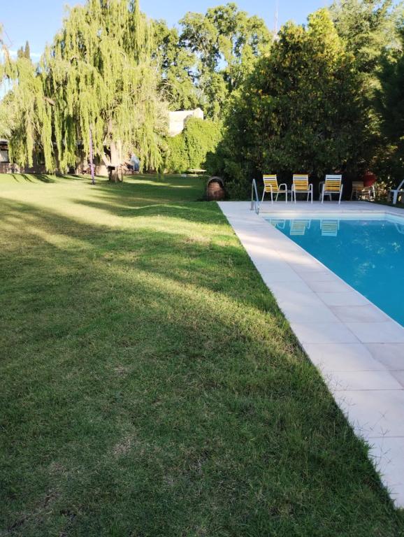 a swimming pool in a yard with chairs in the grass at Tierra Clara Chacras in Ciudad Lujan de Cuyo