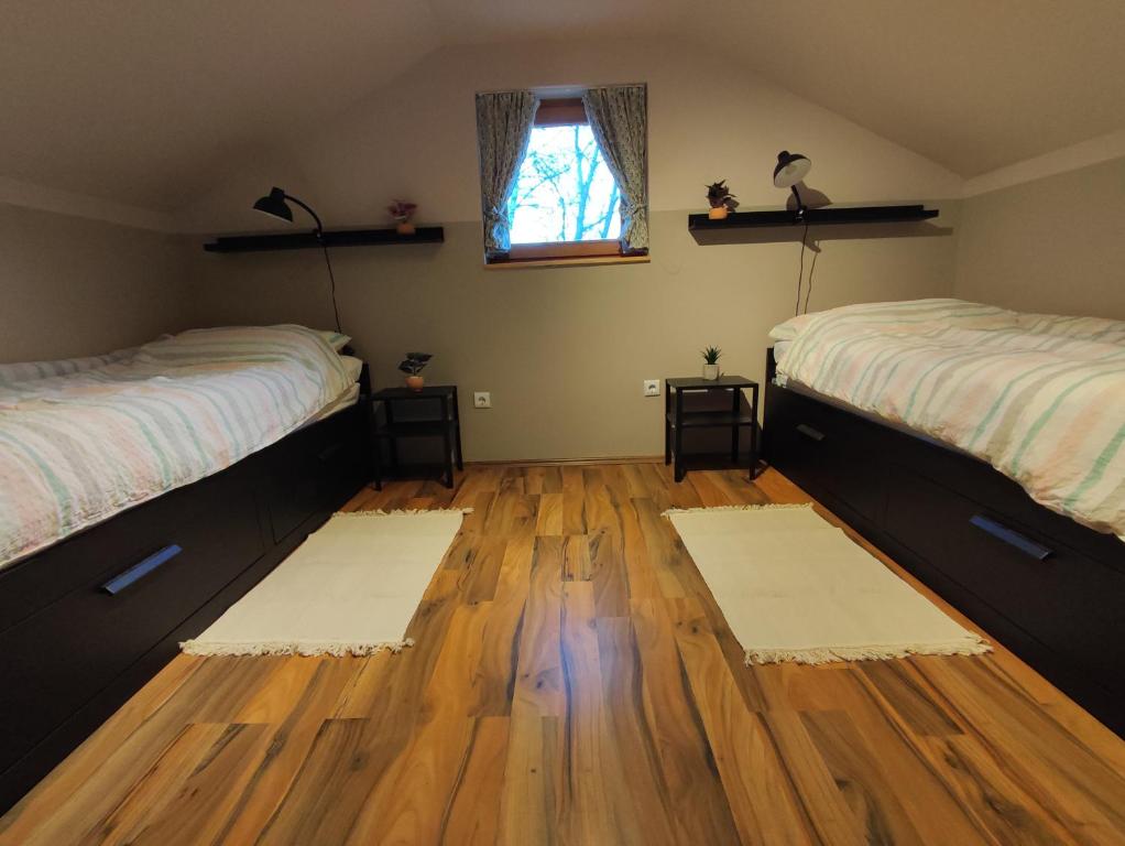 2 Betten in einem Zimmer mit Holzböden und einem Fenster in der Unterkunft Bakino brdo - Granny's hill in Bakovčica