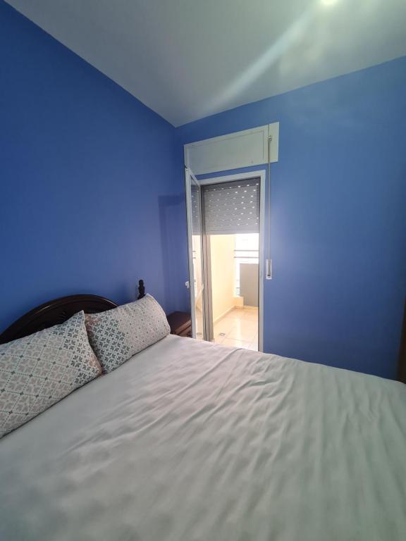 um quarto com uma cama com uma parede azul em appart near the Airport and beach Tanger gzenaya 2 rooms em Tânger