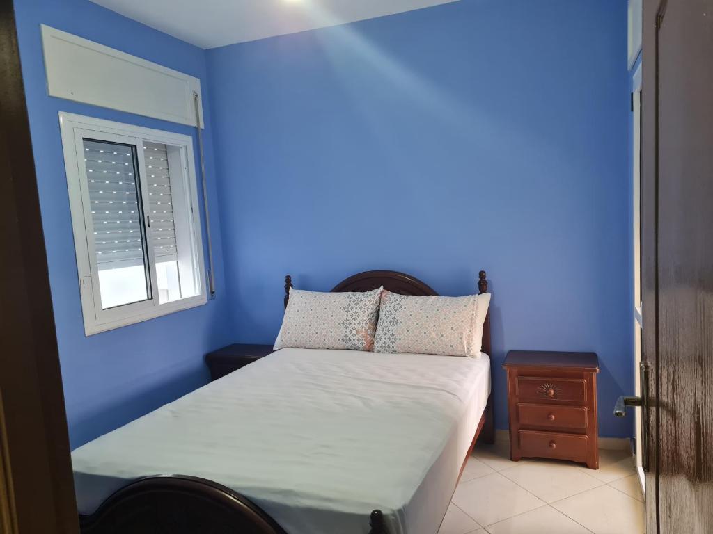 um quarto azul com uma cama e uma janela em appart near the Airport and beach Tanger gzenaya 2 rooms em Tânger