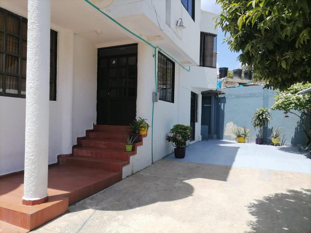 una casa blanca con una puerta negra y escaleras en Hummingbird House, en San Andrés