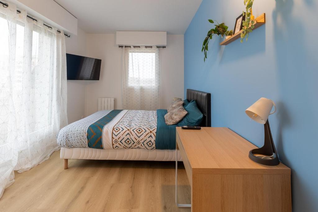 um quarto com uma cama e uma secretária com um candeeiro em Le Beau Refuge Parisien de Cergy - Parisian modern flat at Cergy em Cergy