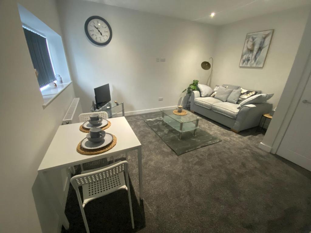 a living room with a couch and a clock on the wall at Entire 1x Bed flat in Bolton