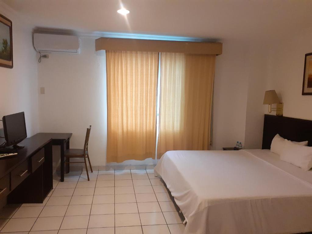 1 dormitorio con cama, escritorio y ordenador en HOTEL DORAL, en Guayaquil