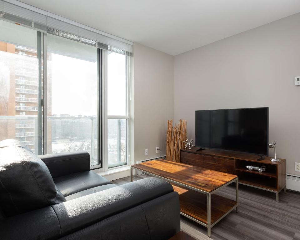 a living room with a couch and a flat screen tv at Hendrix Luxury Apartments by Corporate Stays in Edmonton