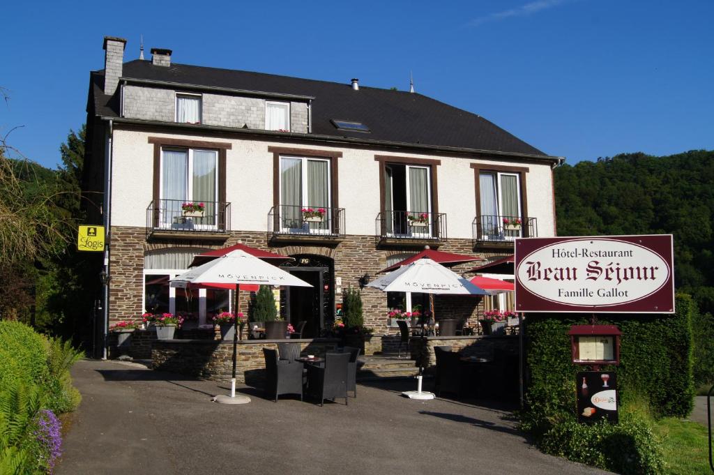 a building with umbrellas and a sign in front of it at Logis Beau Séjour in Frahan