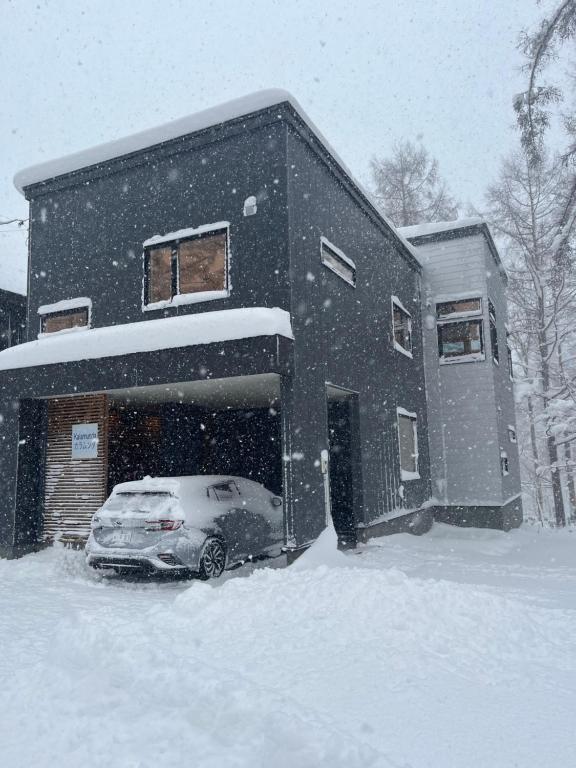 a car parked in front of a building in the snow at Kalamunda House Rusutsu in Rusutsu