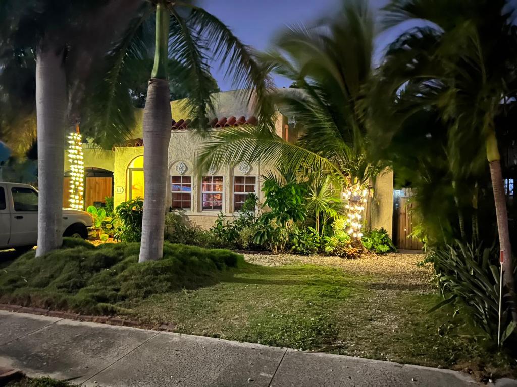 uma casa com palmeiras em frente em The Cottage at Pineapple House em West Palm Beach