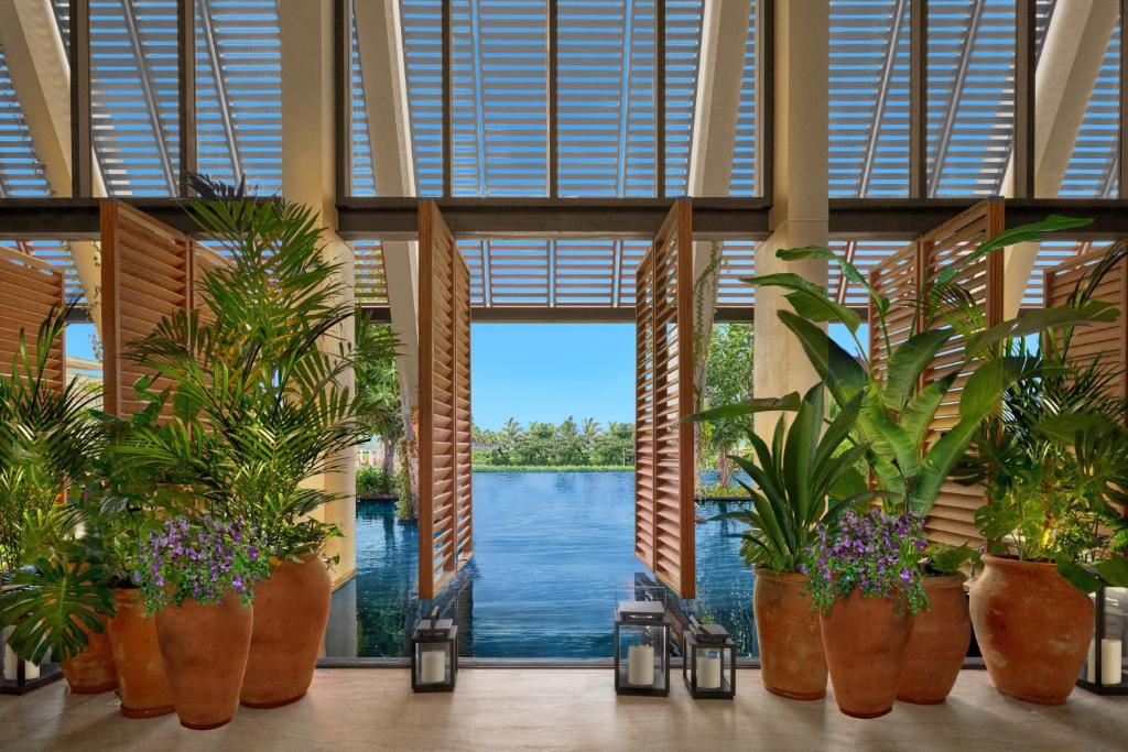 a room with potted plants and a view of the water at The Riviera Maya EDITION at Kanai in Playa del Carmen