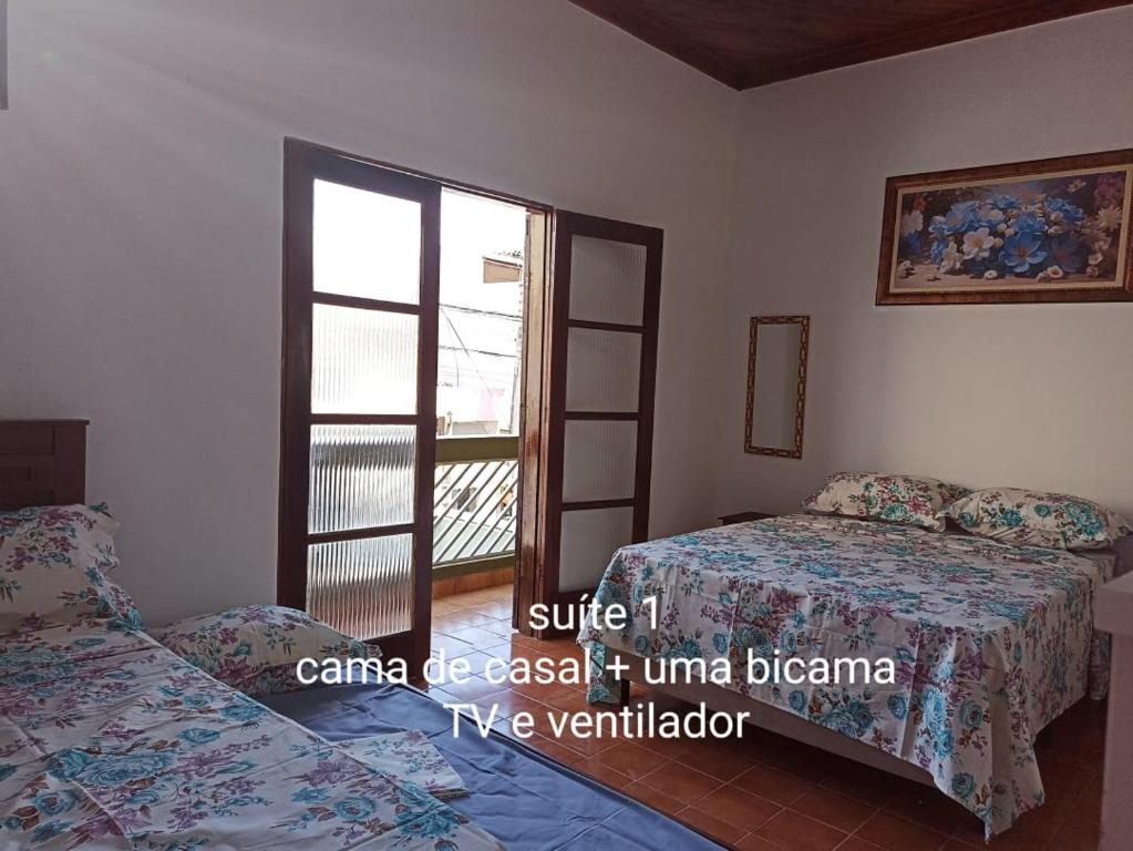 - une chambre avec 2 lits et une fenêtre dans l'établissement Casa para 12 pessoas perto da Basílica e da Feira, à Aparecida