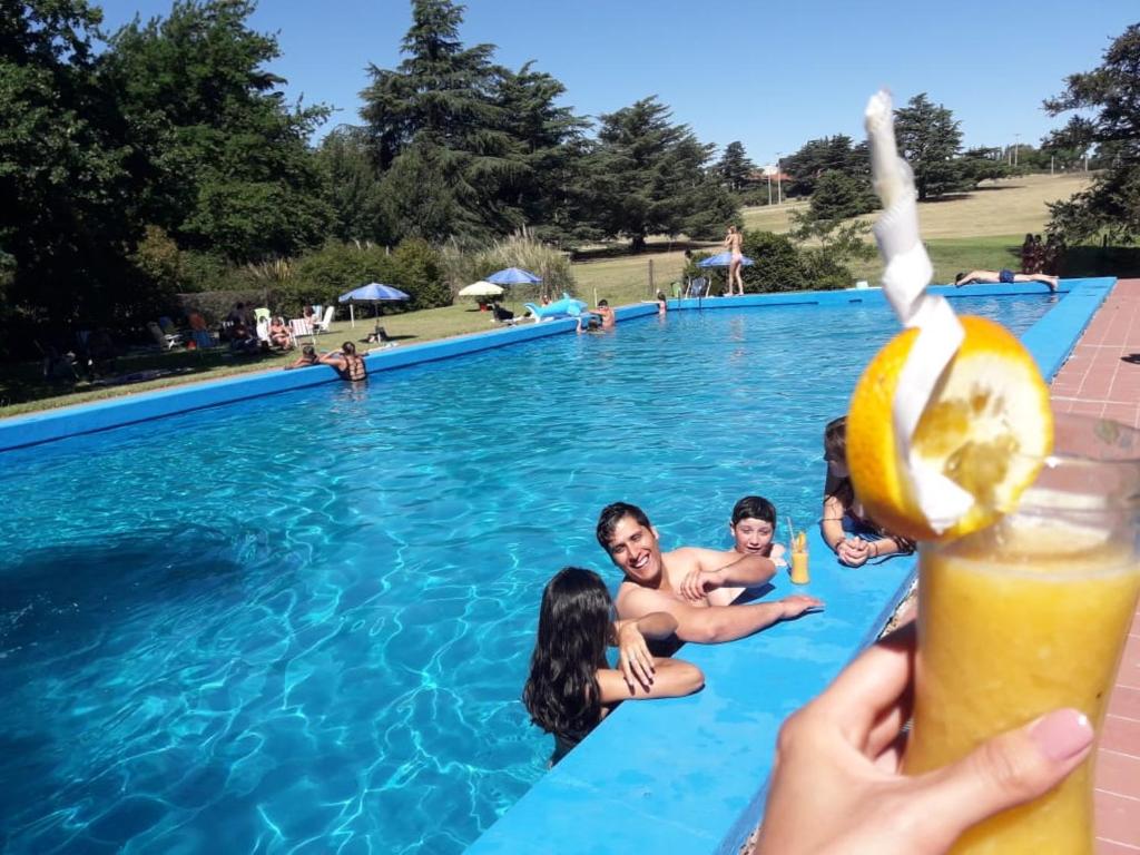 a group of people in a swimming pool with a drink at Apartamentos Villa Tivoli in Sierra de la Ventana
