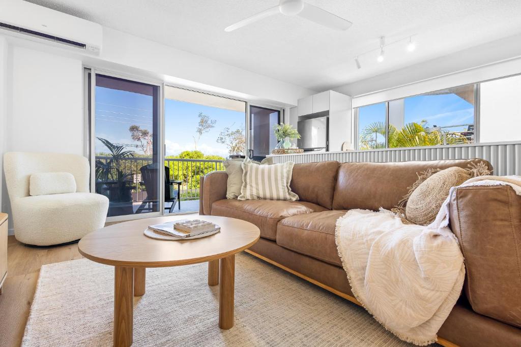 a living room with a brown couch and a table at Maroochydore Beachfront in Maroochydore