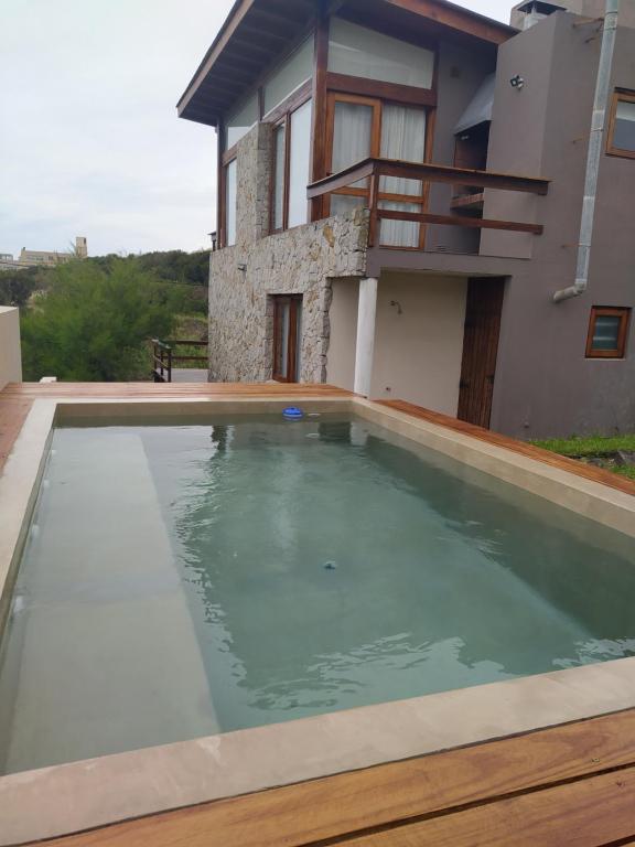 a swimming pool in front of a house at Cabañas Agreste in Villa Gesell