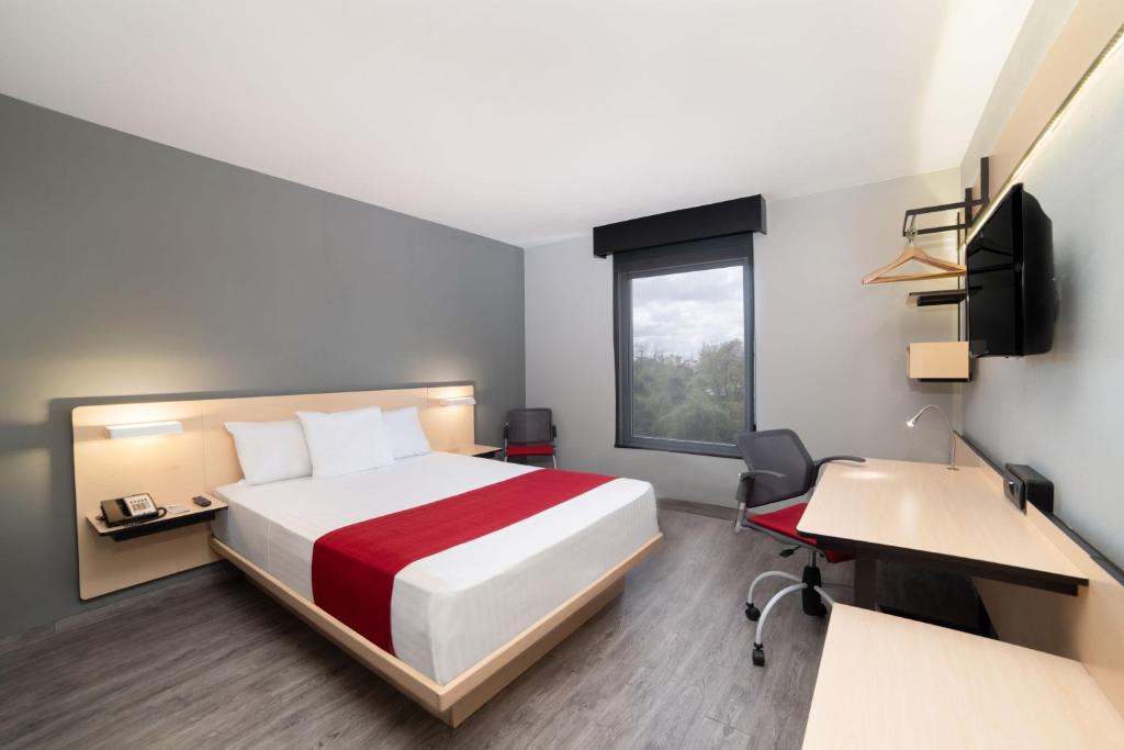 a hotel room with a bed and a desk and a window at City Express by Marriott Puebla Centro in Puebla