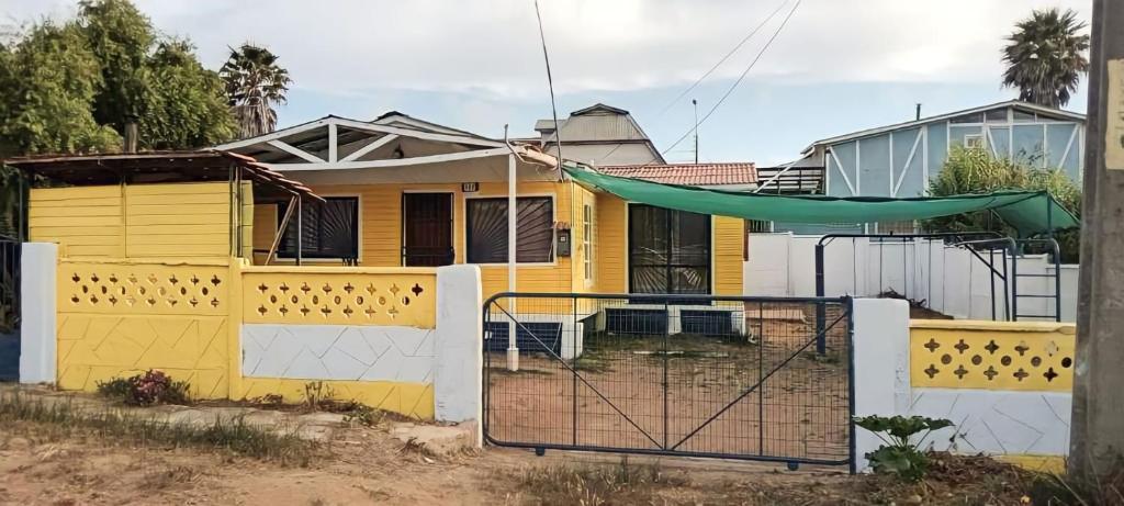 een geel huis met een hek en een hangmat bij Cabaña Las Cruces, a pasos de la playa in Las Cruces