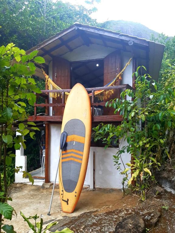 a surfboard sitting in front of a house at Pouso da Cajaíba - Chalé Pedaço de Céu in Paraty