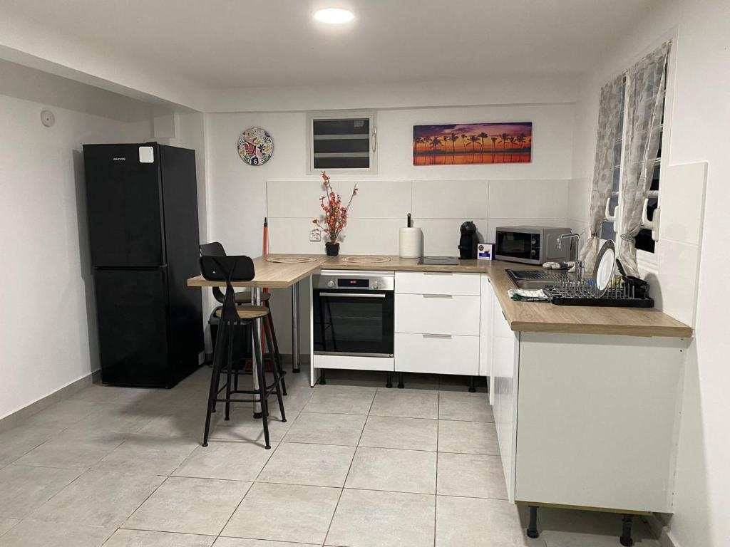 uma cozinha com armários brancos e um frigorífico preto em L Oasis des kassaveries em Capesterre-Belle-Eau