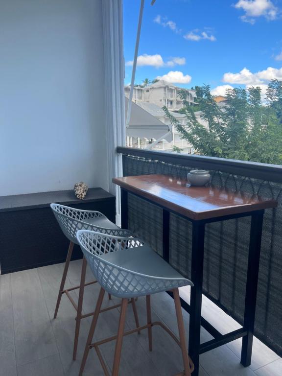 a balcony with a table and two chairs and a window at Duplex Marina gosier- vue Mer et bateaux in Le Gosier