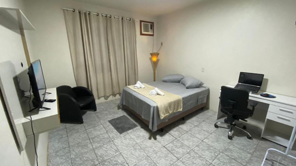 a bedroom with a bed and a desk with a computer at Conforto e tranquilidade no centro in Foz do Iguaçu