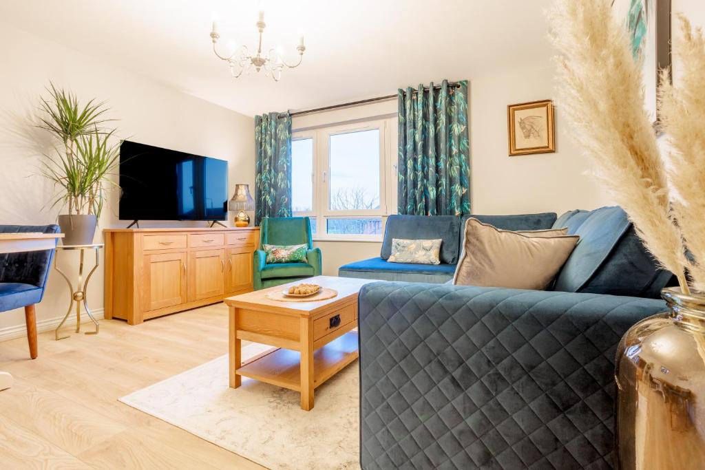 a living room with a blue couch and a tv at Luxurious Scottish Apartment in Perth