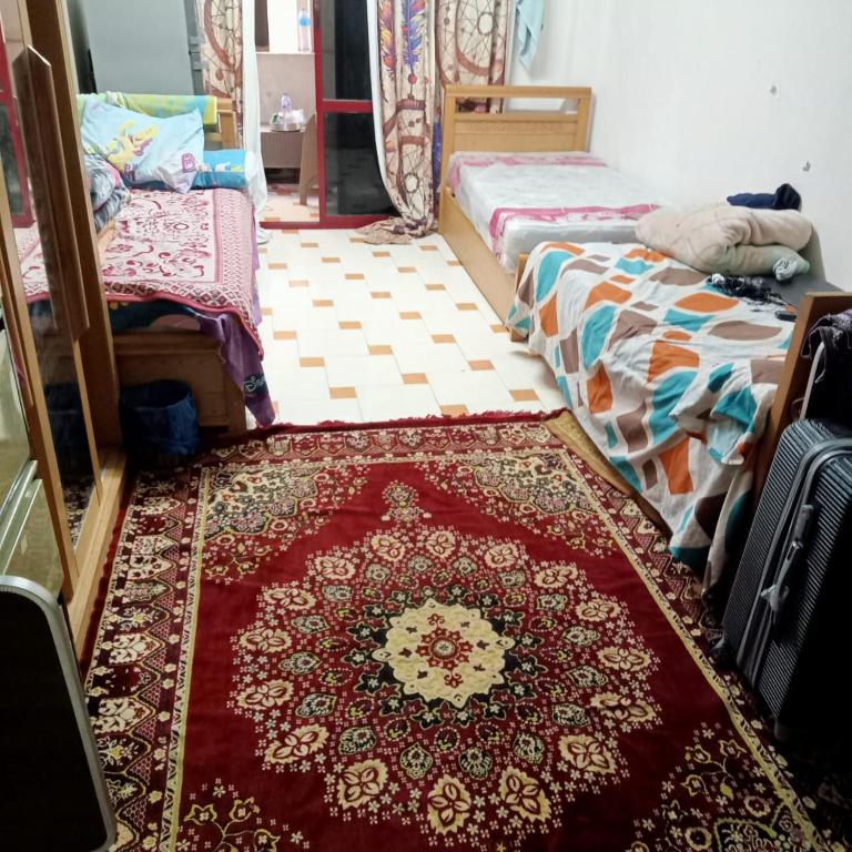 a room with two beds and a rug on the floor at بيت الطالبات والمغتربات in 6th Of October