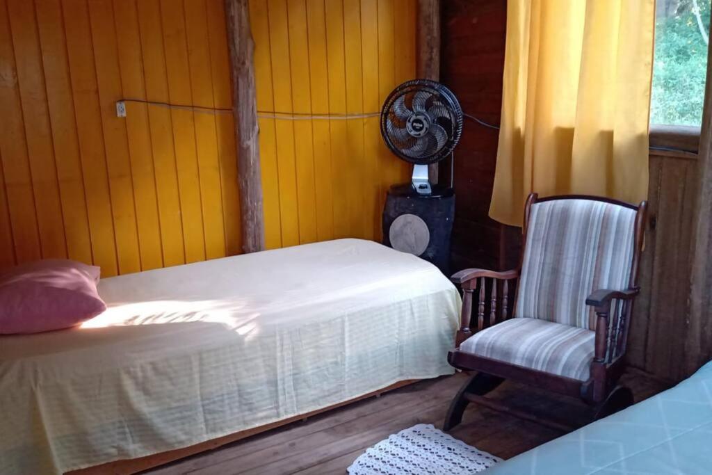 1 dormitorio con 1 cama, 1 silla y ventilador en Casa rústica pertinho das águas en Santo Amaro da Imperatriz
