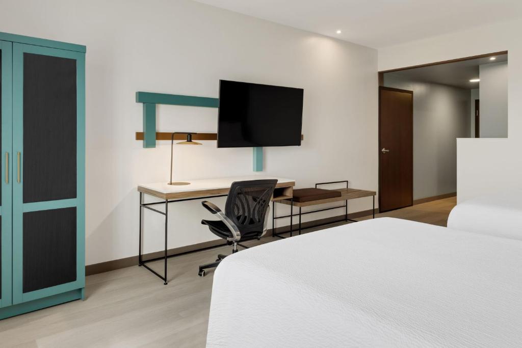 a bedroom with a bed and a desk with a television at Courtyard by Marriott San Jose Airport Alajuela in Alajuela City