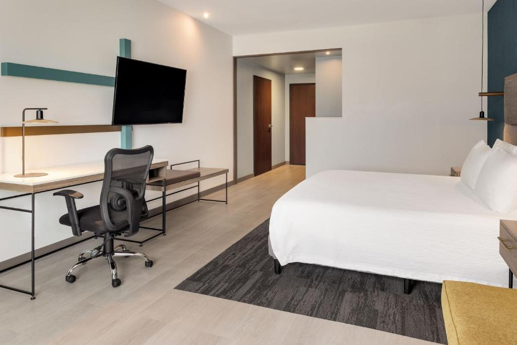 a hotel room with a bed and a desk with a computer at Courtyard by Marriott San Jose Airport Alajuela in Alajuela City