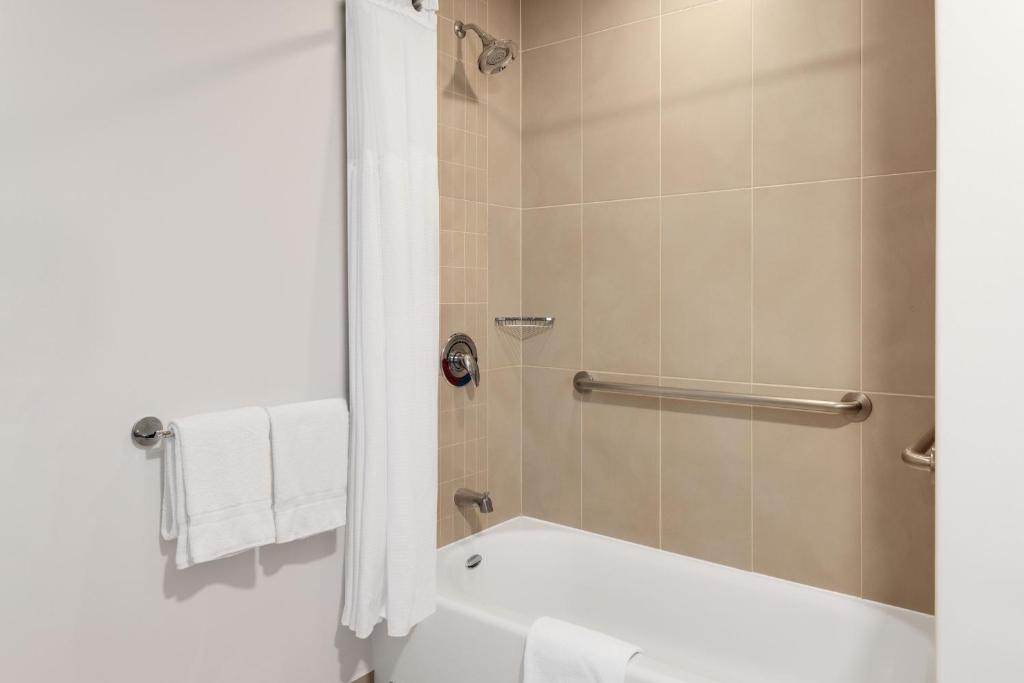 a bathroom with a shower with a tub and a toilet at Courtyard by Marriott San Jose Airport Alajuela in Alajuela City