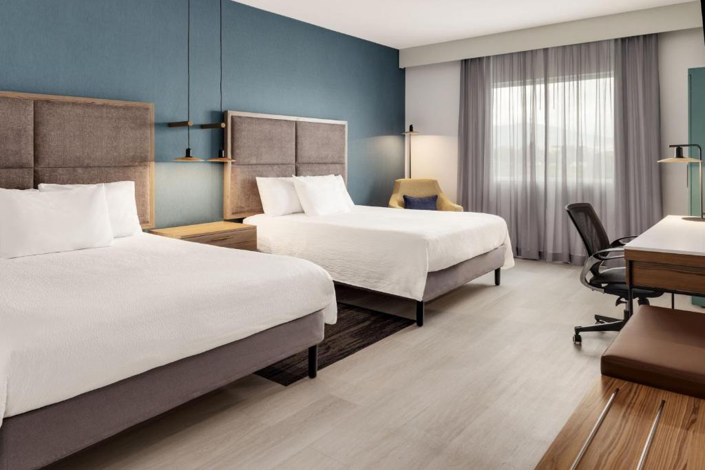 a hotel room with two beds and a desk at Courtyard by Marriott San Jose Airport Alajuela in Alajuela City