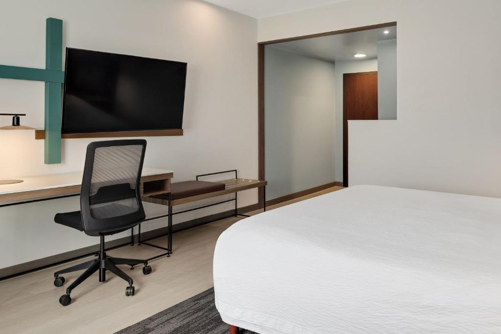a room with a bed and a chair and a tv at Courtyard by Marriott San Jose Airport Alajuela in Alajuela City