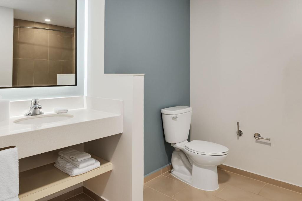 a bathroom with a white toilet and a sink at Courtyard by Marriott San Jose Airport Alajuela in Alajuela City