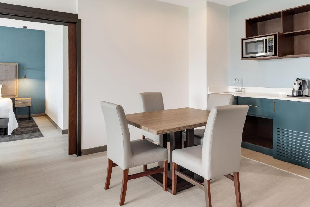 a kitchen and dining room with a wooden table and chairs at Courtyard by Marriott San Jose Airport Alajuela in Alajuela City
