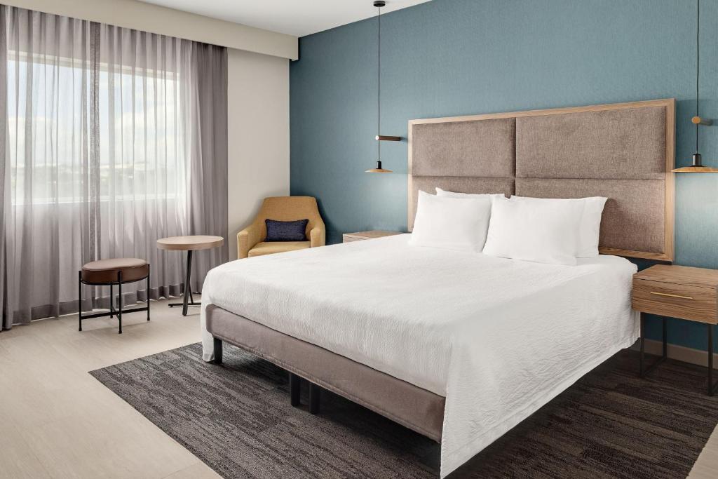 a bedroom with a large bed and a chair at Courtyard by Marriott San Jose Airport Alajuela in Alajuela City