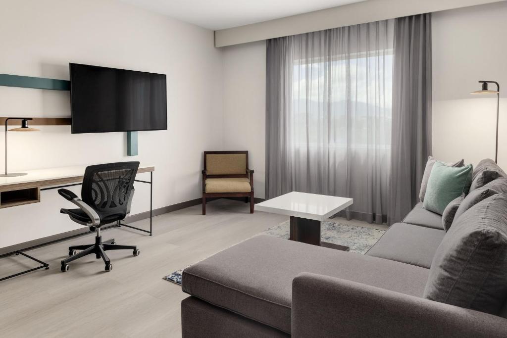 a living room with a couch and a desk at Courtyard by Marriott San Jose Airport Alajuela in Alajuela City
