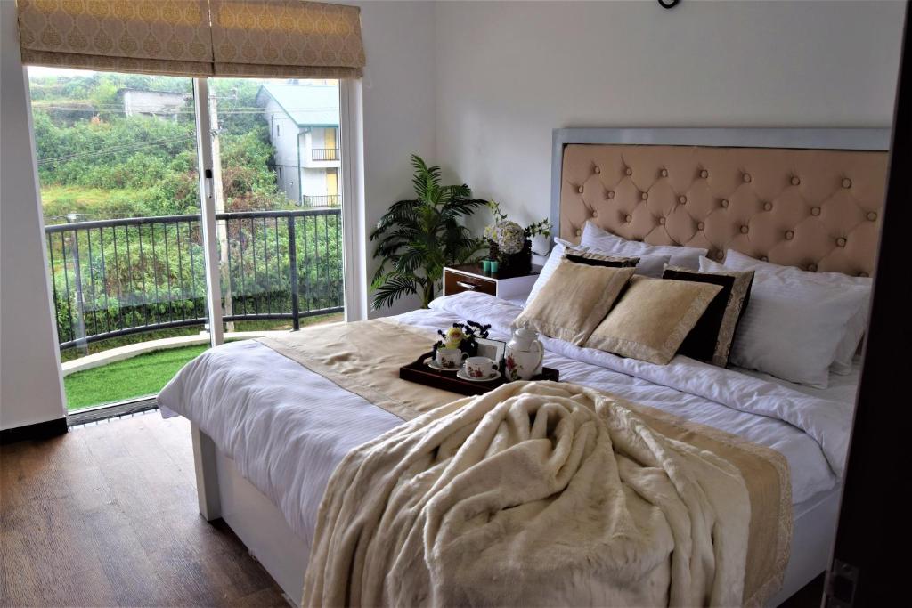 a bedroom with a large bed with a large window at Infinity Condos by Lake Infinity in Nuwara Eliya