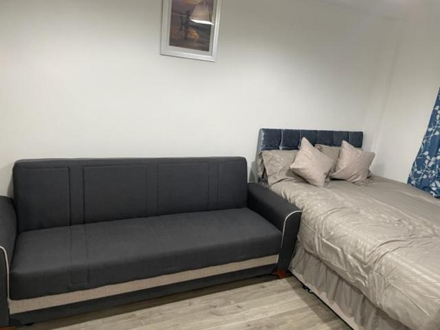 czarna kanapa obok łóżka w pokoju w obiekcie Luxury Leytonstone Studio flat w Londynie