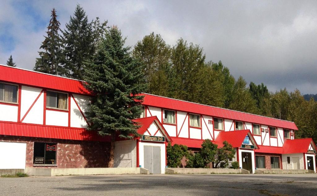 ein rot-weißes Gebäude mit einem Baum davor in der Unterkunft Villagers Inn in Fruitvale