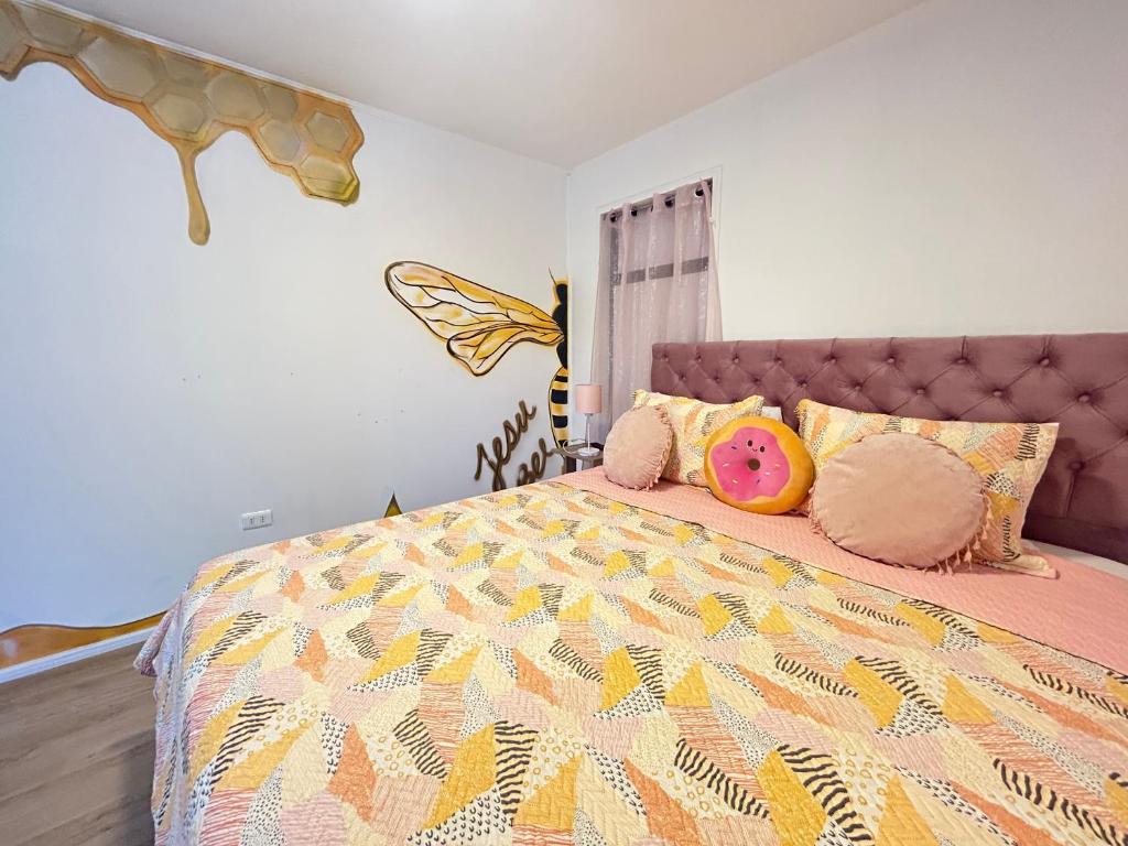 a bedroom with a large bed with pink and yellow comforter at Miel House Villa Alemana Beehouse in Villa Alemana