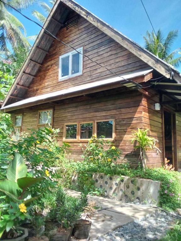 een houten huis met planten ervoor bij Bird Friendly Inn in Bayawan