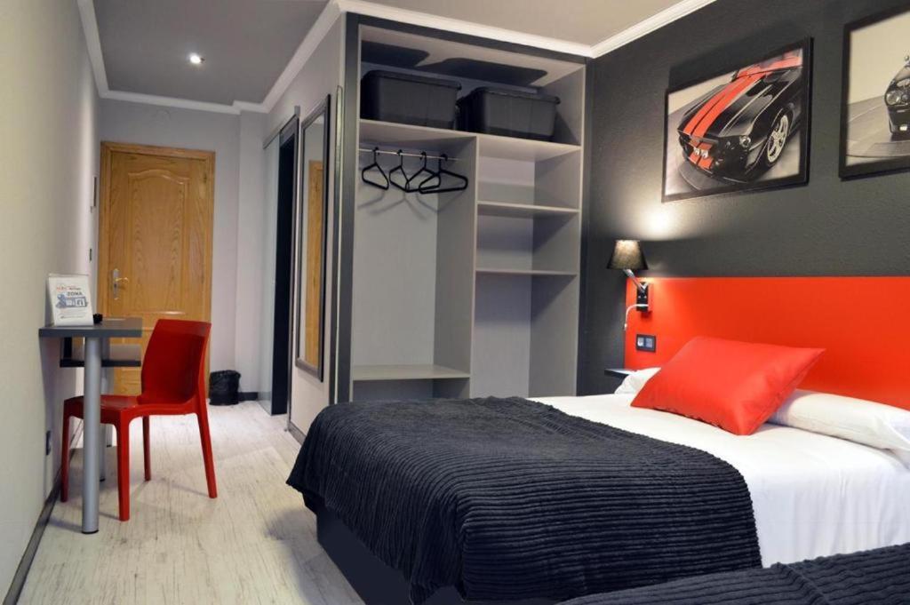 a bedroom with a bed with an orange headboard and a desk at HOTEL CEAO in Lugo